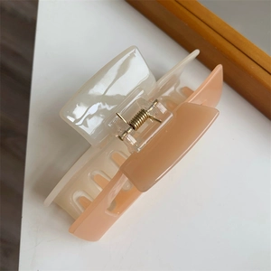 Close-up of a large cream and peach bicolor hair claw clip with a strong gold metal spring