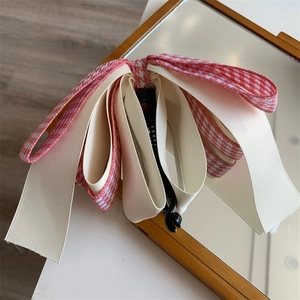 Détail d'une pince banane avec nœud multicouche à motif pied-de-poule rose et crème