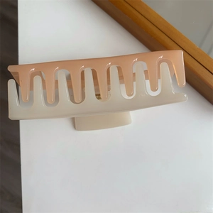 Detail view of large two-tone hair claw clip in soft pink and cream with matte finish