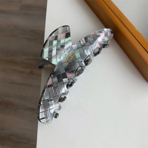 Détail macro d'une pince à cheveux mosaïque grise avec finition nacrée texture coquillage