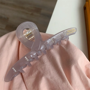 Détail de la pince à cheveux en acétate violet avec strass et texte doré Barrette