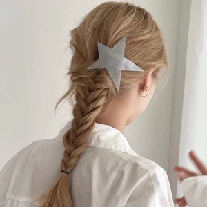 Close-up of a silver star hair clip with glitter finish on a model's blonde hair