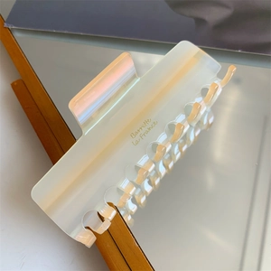 Détail d'une pince à cheveux en acétate nacré crème avec inscription Barrette La France