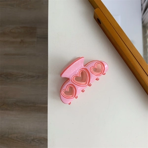 Vue détaillée de la pince à cheveux cœur rose évidé avec design en résine superposée