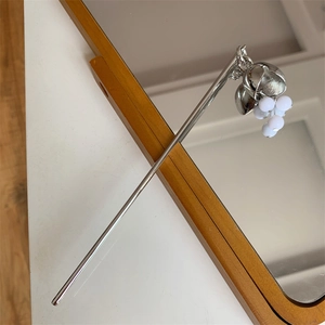 Détail d'un pic à cheveux en métal argenté avec pendentifs muguet et perles blanches