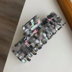 Vue détaillée d'une pince à cheveux à carreaux mosaïques avec une texture de nacre grise