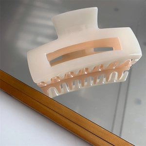 Detailed view of cream square hair claw clip with smooth finish on a mirror surface