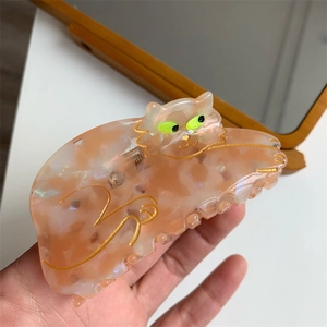 Detailed close-up of pink marble acetate hair claw clip featuring golden cat design details
