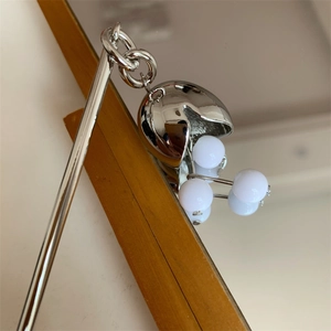 Détail d'une épingle à cheveux argentée avec pendentif et perles blanches sur miroir