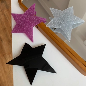 Detailed view of trendy irregular star hair clips in glittery pink, silver, and glossy black