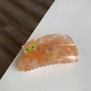 Detail showing high-quality acetate orange cat hair claw clip with golden outlines