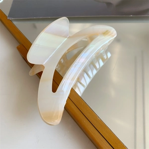 Détail d'une pince à cheveux en acétate crème avec effet nacré sur un miroir