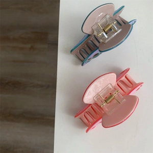 Détail de deux pinces à cheveux en acrylique aux tons bleu morandi et rose corail