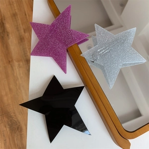 Three trendy star-shaped hair clips in purple glitter, silver glitter, and black finish