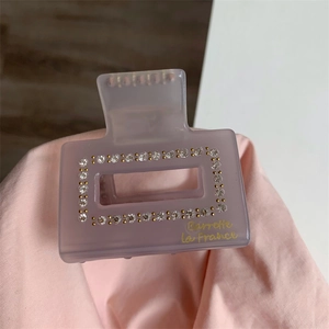 Vue détaillée de la pince à cheveux en acétate gris avec strass et texte doré