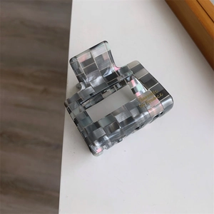 Détail d'une pince à cheveux carrée à carreaux gris avec une finition nacrée