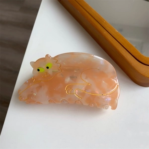 Detail of cute orange cat hair claw clip made of tortoiseshell acetate with marble texture
