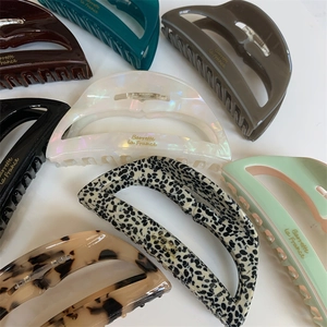 Detailed collection of assorted acetate hair claws with premium golden lettering logos