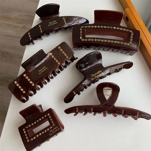 Elegant deep brown crystal hair claw clips collection with gold-tone letter detailing