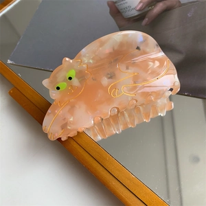 Detailed close-up of a cute orange cat hair claw clip with green eyes in a mirror reflection