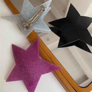 Detailed view of silver, black and purple glitter star hair clips on a mirror