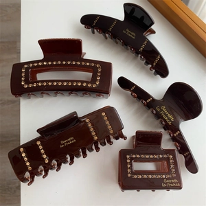 Detailed view of amber hair claws with rhinestones and gold Barrette La France text
