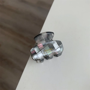 Détail de la pince à cheveux en acétate à carreaux gris avec lettrage doré Barrette