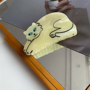 Macro shot of a cream acetate cat hair claw clip reflected in a mirror surface