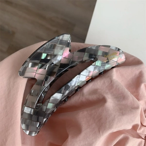 Détail d'une pince à cheveux en acétate à damier gris avec texte doré Barrette la France