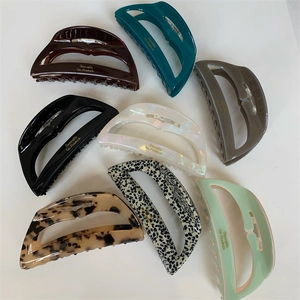 Detailed close-up showing eight different colors of large acetate hair claw clips with gold labels