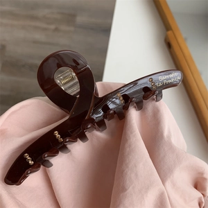 Close-up of elegant burgundy hair claw clip with golden lettering and small rhinestones