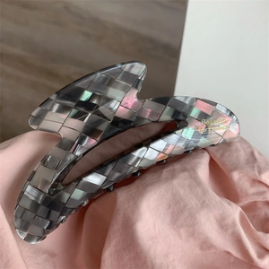 Vue détaillée d'une grande pince à cheveux en acétate avec motif à carreaux gris et rose