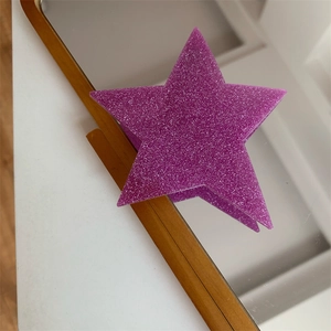 Detailed view of a purple star hair clip with glittering finish on a mirrored surface