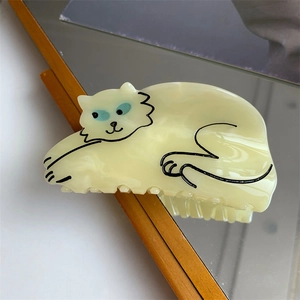 Detailed close-up of a cute cream cat hair claw clip reflected in a wooden mirror frame