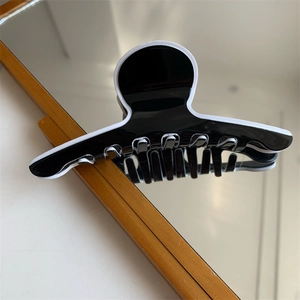 Vue détaillée de la pince à cheveux élégante noire et blanche en résine brillante