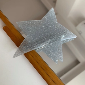 Macro detail of a layered black glitter star hair clip with shimmering silver sparkles
