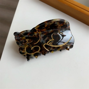 Detailed macro view of tortoiseshell cat hair claw clip with golden outline details