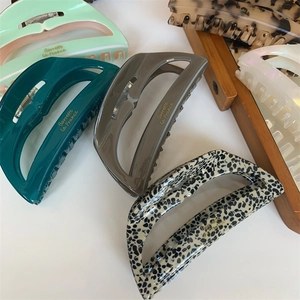 Close-up of acetate shark hair claw clips in various colors with gold lettering