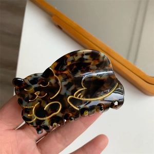 Detailed close-up of a tortoiseshell cat hair claw clip with elegant gold outlines