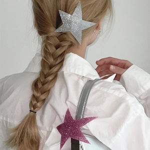 Glittery star-shaped hair clips in silver and purple worn on braided hair for women