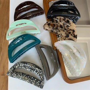 Minimalist acetate hair claws in various colors and patterns with gold lettering detail