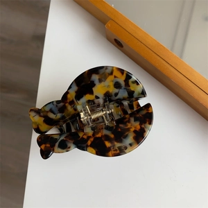 Macro view of tortoiseshell hair claw clip with golden metal spring on white surface