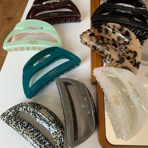Large acetate hair claws in various colors with elegant golden lettering accents