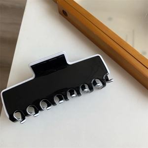 Détail d'une pince à cheveux élégante noire et blanche en acrylique avec bordure chic