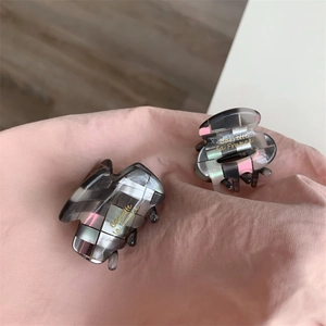 Détail de deux pinces à cheveux à carreaux gris avec lettrage Barrette la France doré