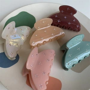 Lot de cinq pinces à cheveux colorées en acrylique avec strass en étoile sur un plateau