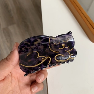Detail view of tortoiseshell cat claw clip held in hand showing purple textures