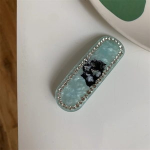 Macro shot of mint green marble oval hair clip with sparkling rhinestones and cat print