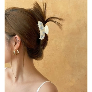 Dettaglio della pinza per capelli crema con fiori blu sull'acconciatura della modella