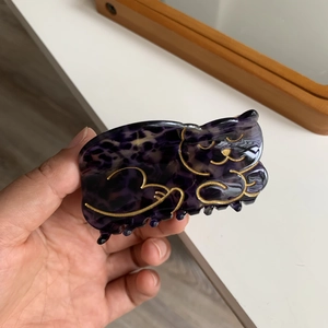 Detailed view of a purple tortoiseshell cat-shaped hair claw clip with gold accents